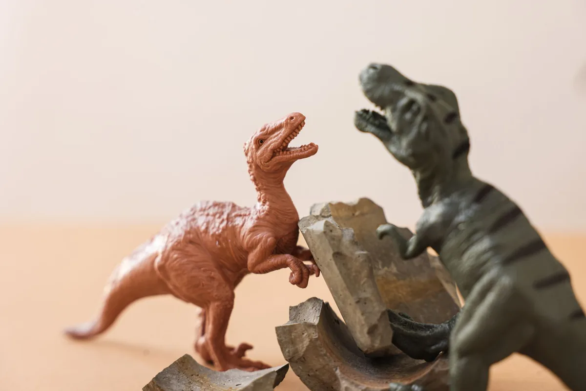 Close-up of colorful dinosaur figurine toys engaged in a playful battle.